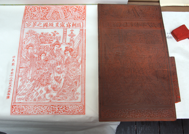 红色雕版印刷年画作品与对应雕刻木版并排展示，体现雕版印刷工艺
