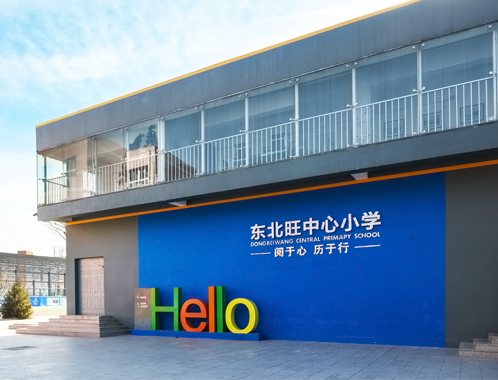 东北旺中心小学教学楼建筑外观，蓝色墙面Hello标语与校徽，校园环境建设