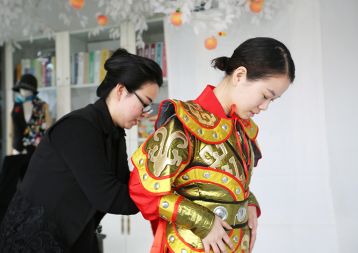 锦连环身着大圣金色戏服的女员工弯腰与同事互动