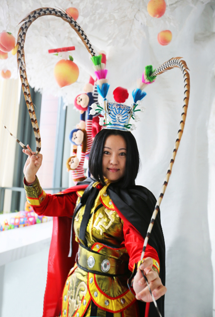 锦连环身着戏服的女员工站在挂满仙桃的白色装饰树旁