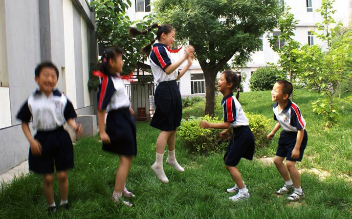 海淀区民族小学学生着校服在校园草坪活动,展现校服应用设计