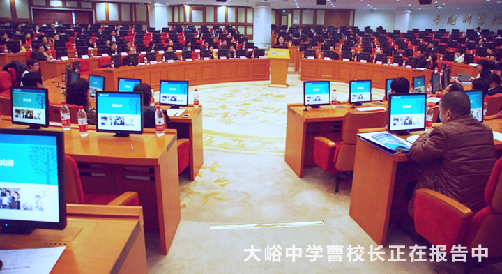 大峪中学品牌发布报告会现场，机房内师生满座，画面字幕显示大峪中学曹校长正在报告